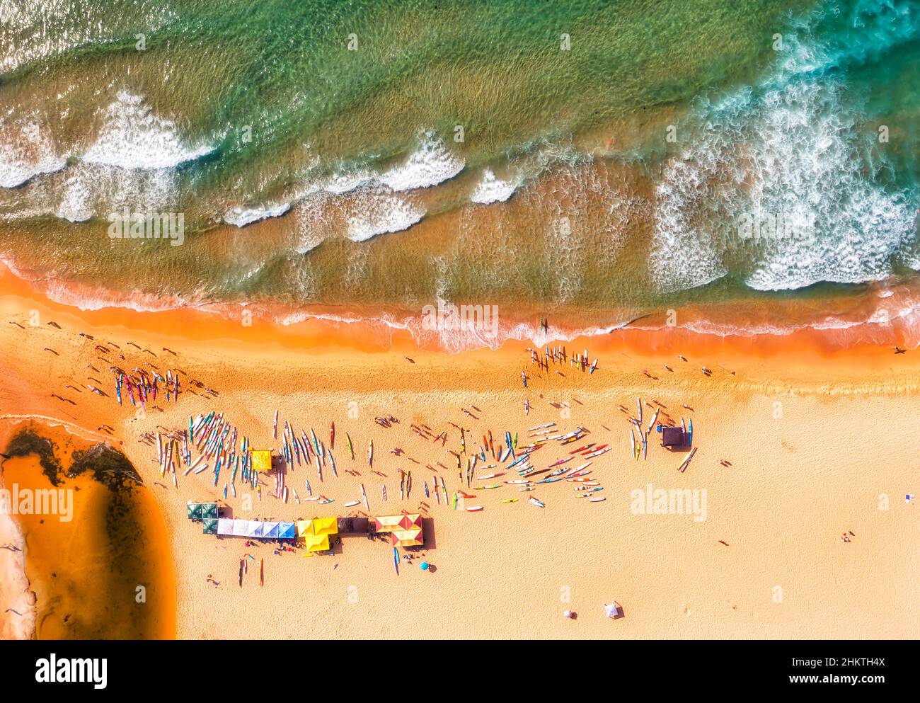 Kayaks and beach goers on Curl Curl beach of Sydney Northern beaches in aerial top down view. Stock Photo
