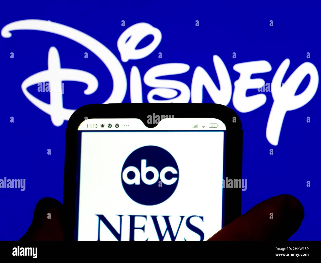 In this photo illustration, the ABC news logo is displayed on a smartphone screen with a Disney logo in the background Stock Photo