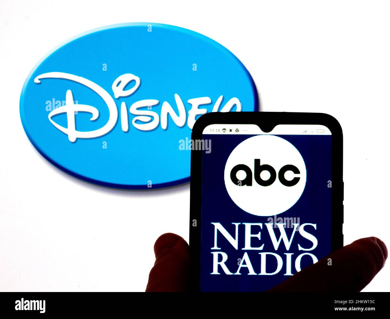 In this photo illustration, the ABC News Radio logo is displayed on a smartphone screen with a Disney logo in the background Stock Photo