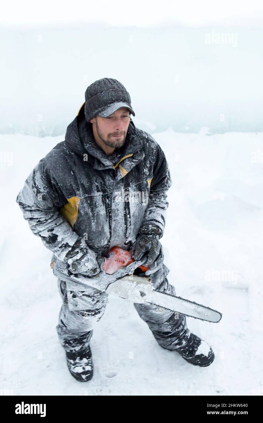 Worker with a chainsaw in hand at the assembly site Stock Photo
