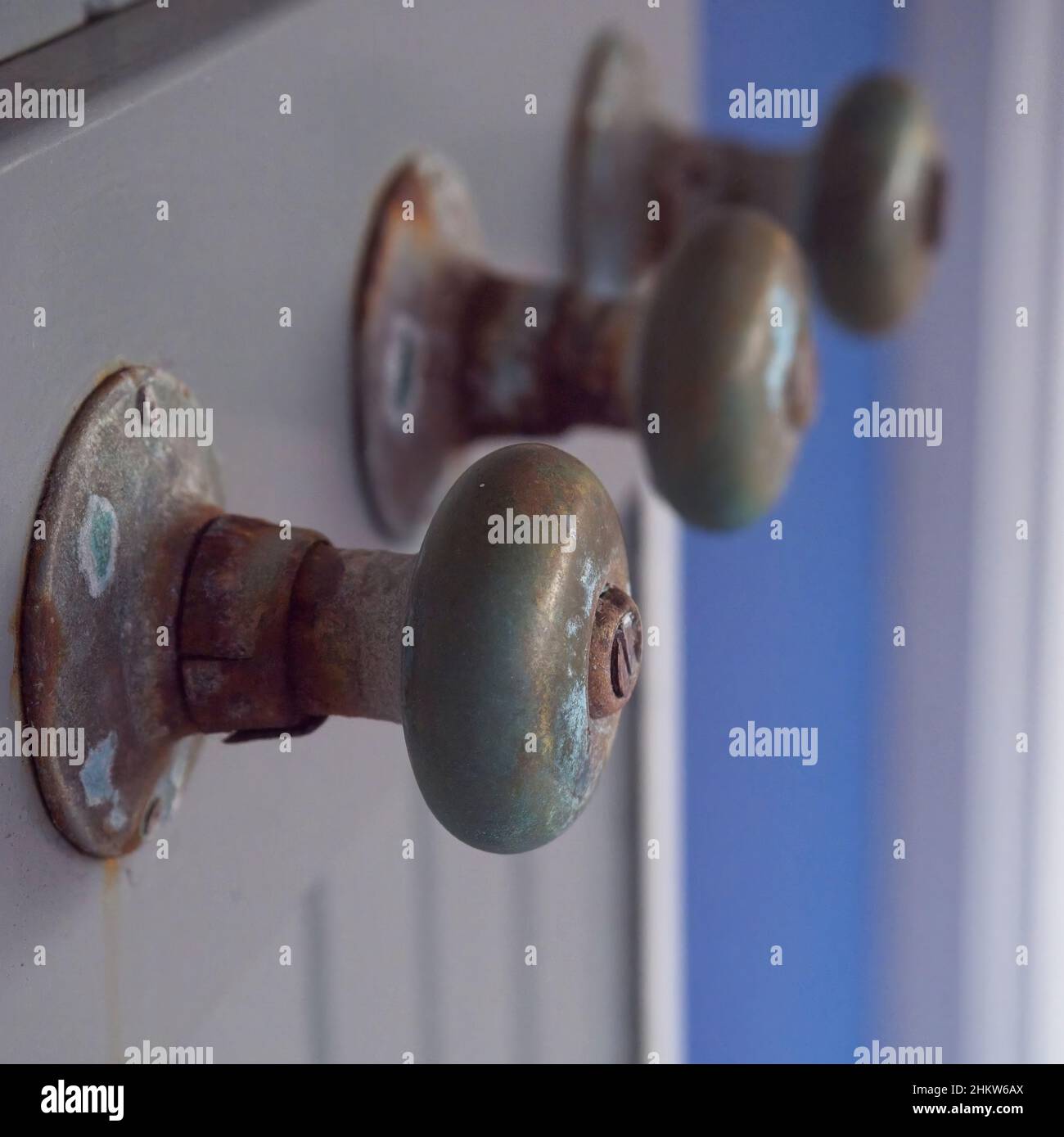 Old door knobs used as coat hangers, exposed to elements Stock Photo