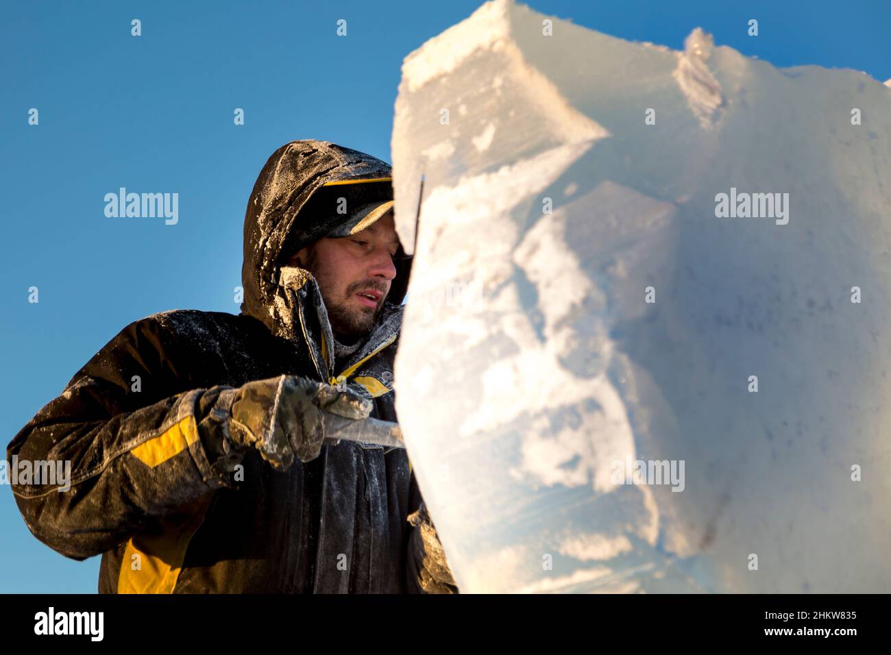 The sculptor cuts an ice figure out of an ice block with a chisel Stock ...