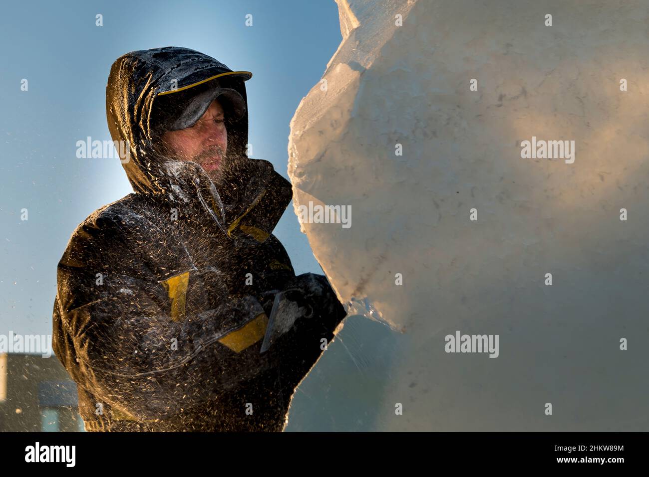 The sculptor cuts an ice figure out of an ice block with a chisel Stock ...