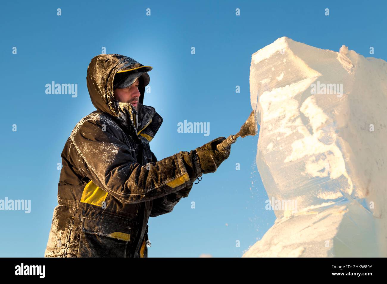 The sculptor cuts an ice figure out of an ice block with a chisel Stock ...