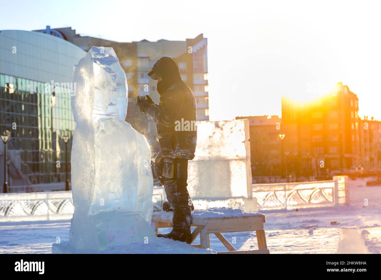 The sculptor cuts an ice figure out of an ice block with a chisel Stock ...