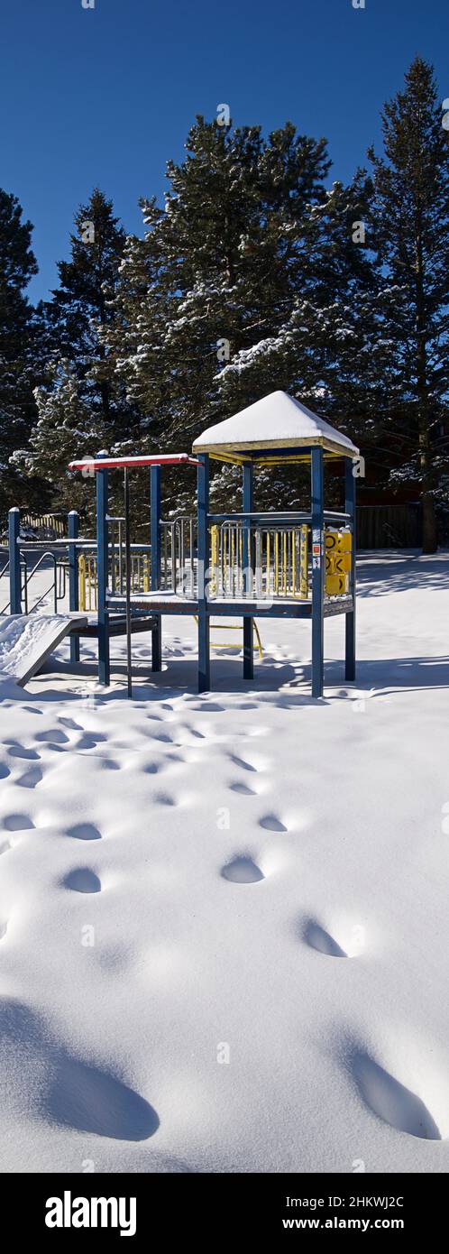 Panoramic vertical photo of the Slide - Kids play area equipment covered with snow with foot print in the public park.  Vertical format background pho Stock Photo