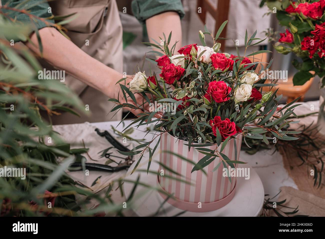 Florist make gift bouquets in hat boxes. Graceful female hands make a beautiful bouquet. Florist workplace. Small business concept. Front view. Flower Stock Photo