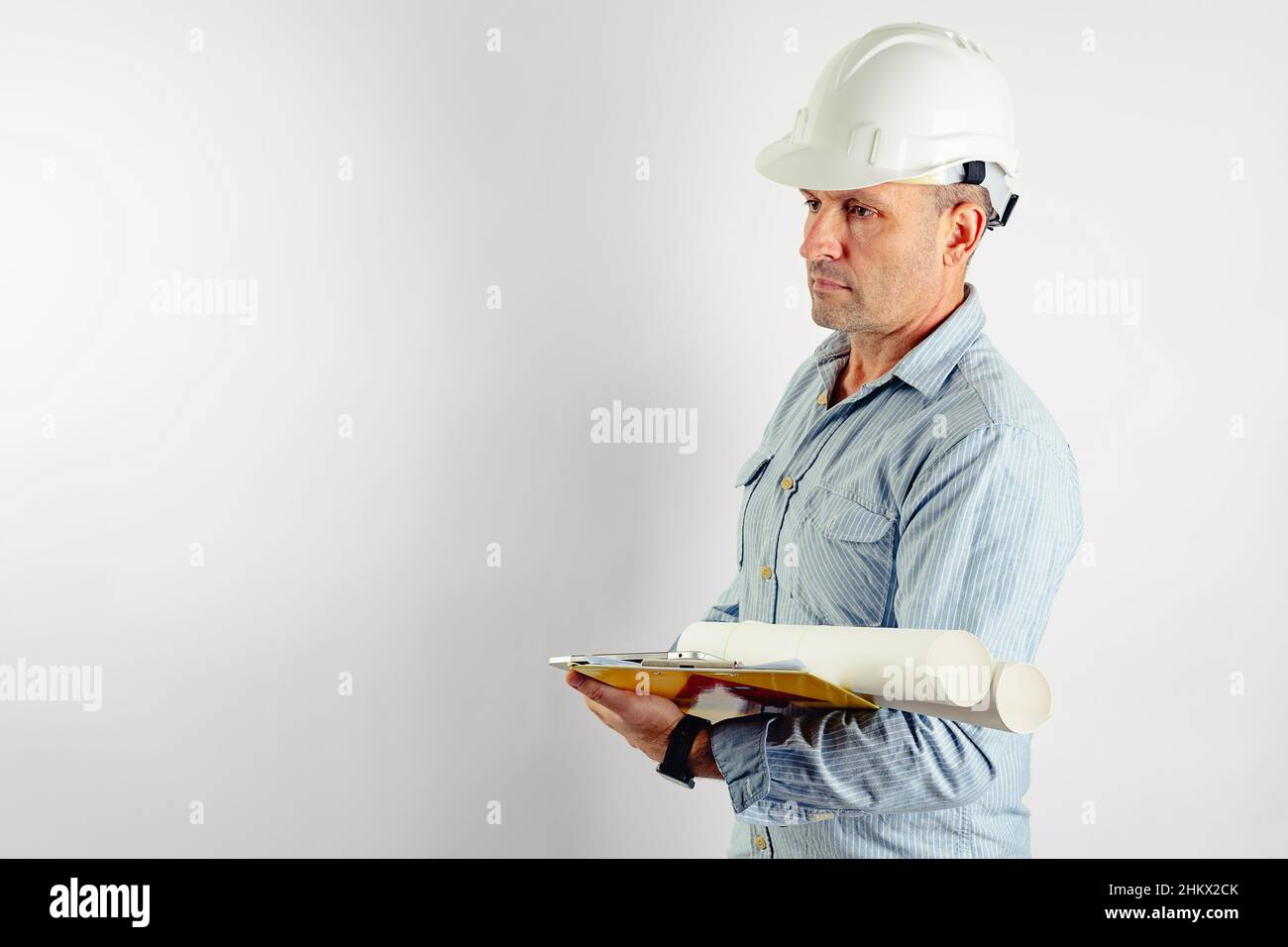 A middle-aged male foreman in a light-colored shirt and a white hard helmet. Isolated portrait on a white background. Copy space. Male stock photo Stock Photo