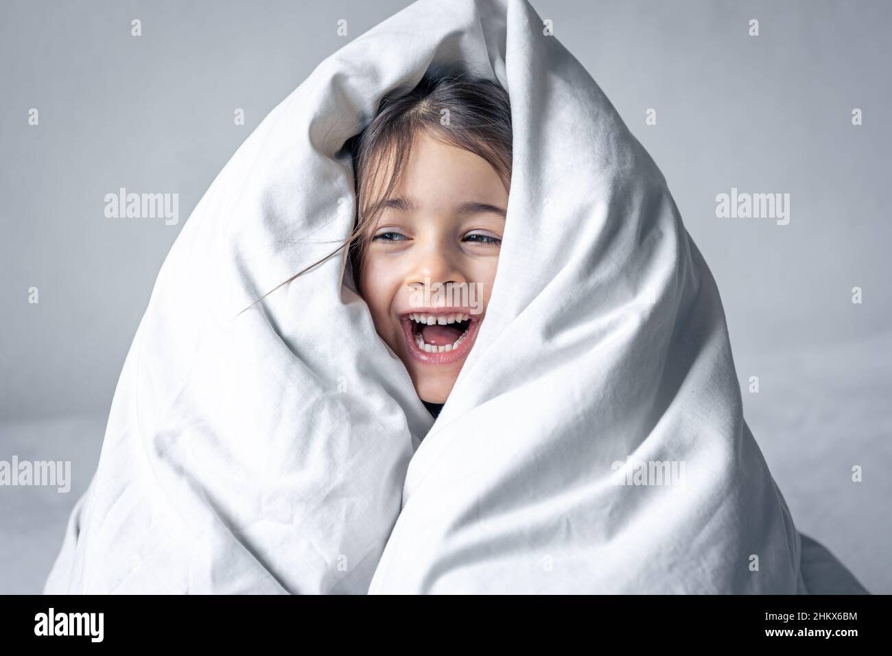 Sleepy little girl wrapped in a white blanket Stock Photo - Alamy