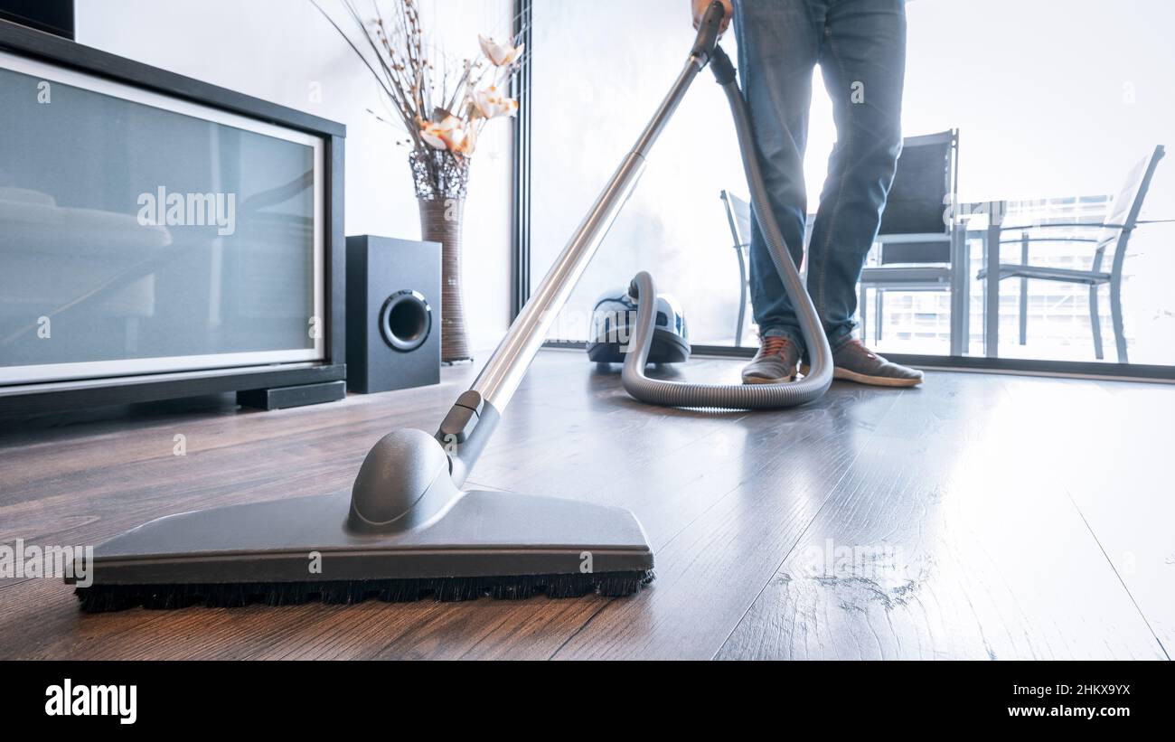 Man cleaning the house with a portable vacuum cleaner Stock Photo