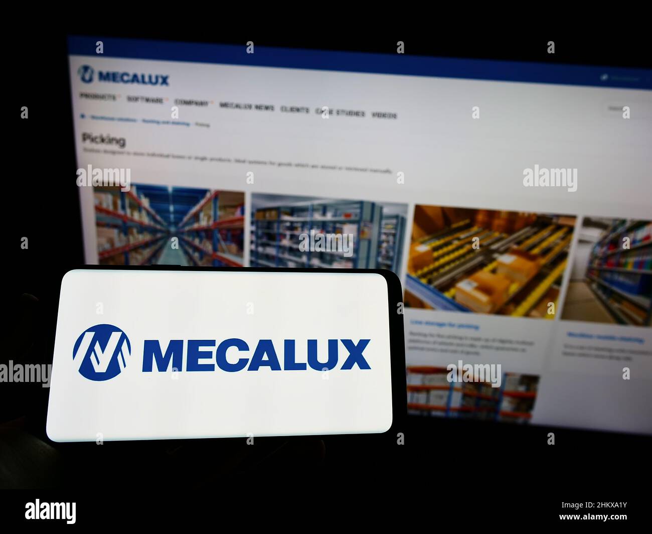 Person holding mobile phone with logo of Spanish logistics company Mecalux SA on screen in front of business web page. Focus on phone display. Stock Photo