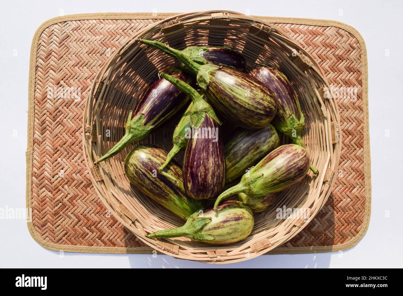 Purple and green striped dua coloured Brinjals in basket. Aubergine or Eggplant vegetable from South Asian India Gujarat. Stock Photo