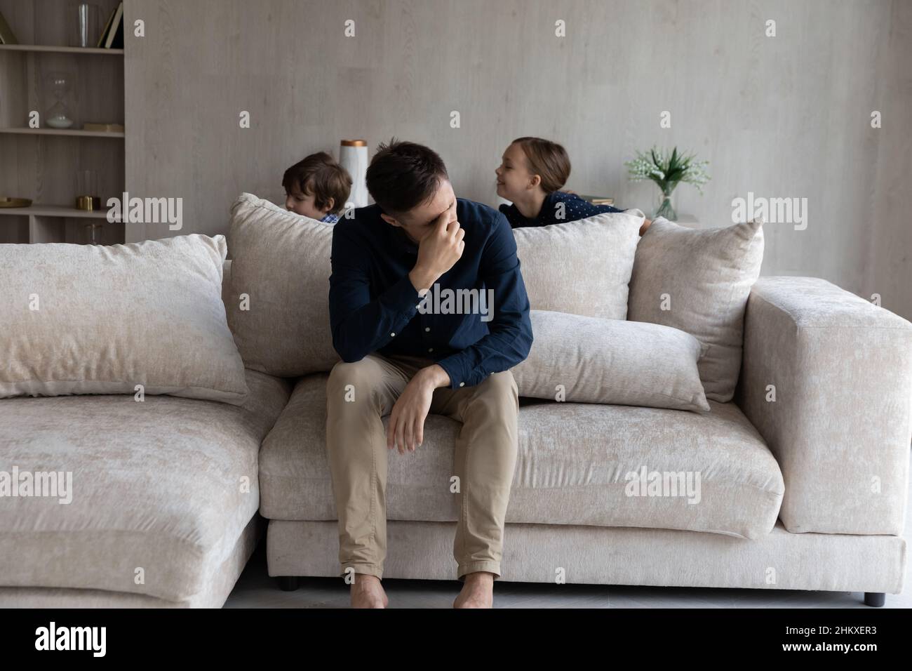 Tired father suffering from headache, exhausted by noisy kids Stock Photo