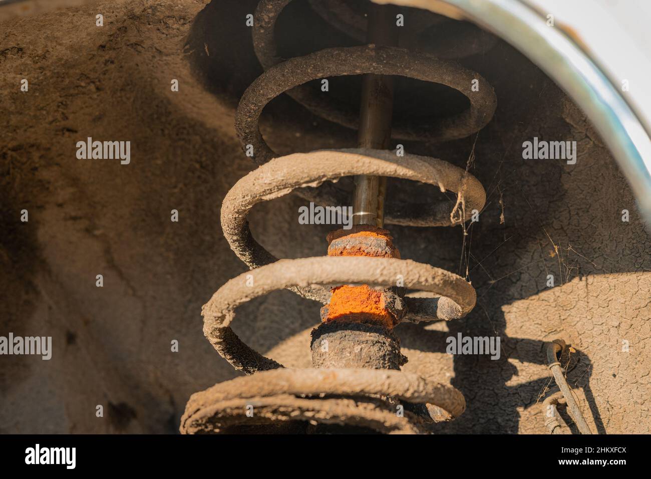 Worn shock absorber on an older car. Visible traces of oil on shock
