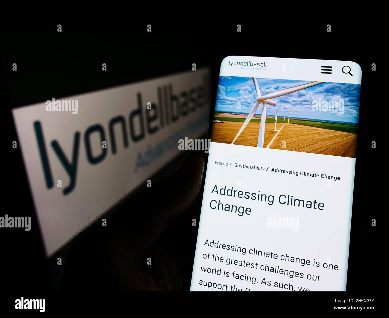Person holding cellphone with website of chemical company LyondellBasell Industries NV on screen with logo. Focus on center of phone display. Stock Photo