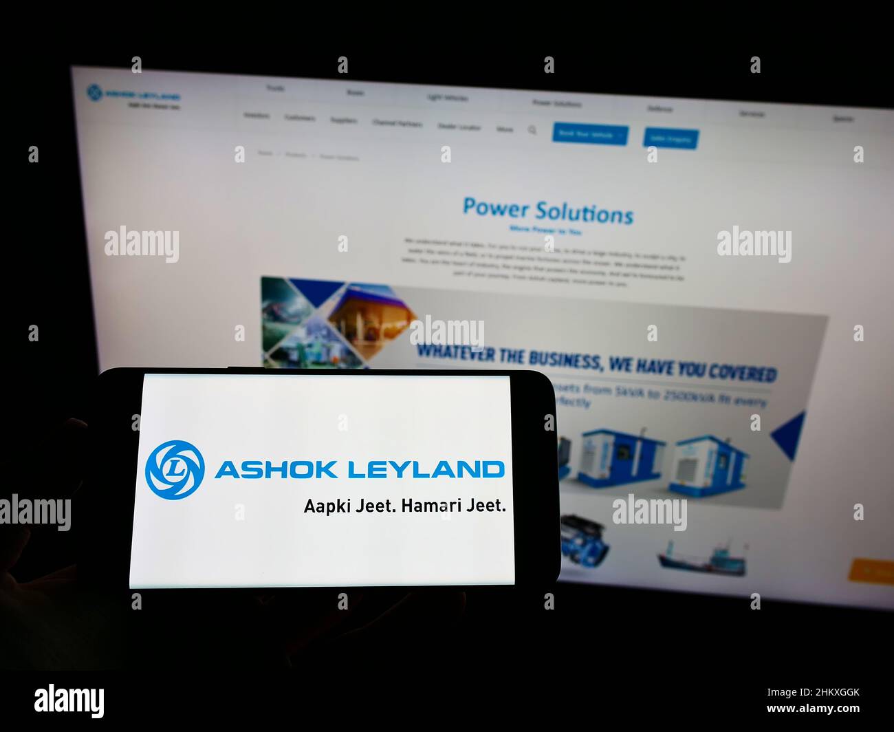 Person holding mobile phone with logo of Indian automotive company Ashok Leyland Ltd. on screen in front of web page. Focus on phone display. Stock Photo