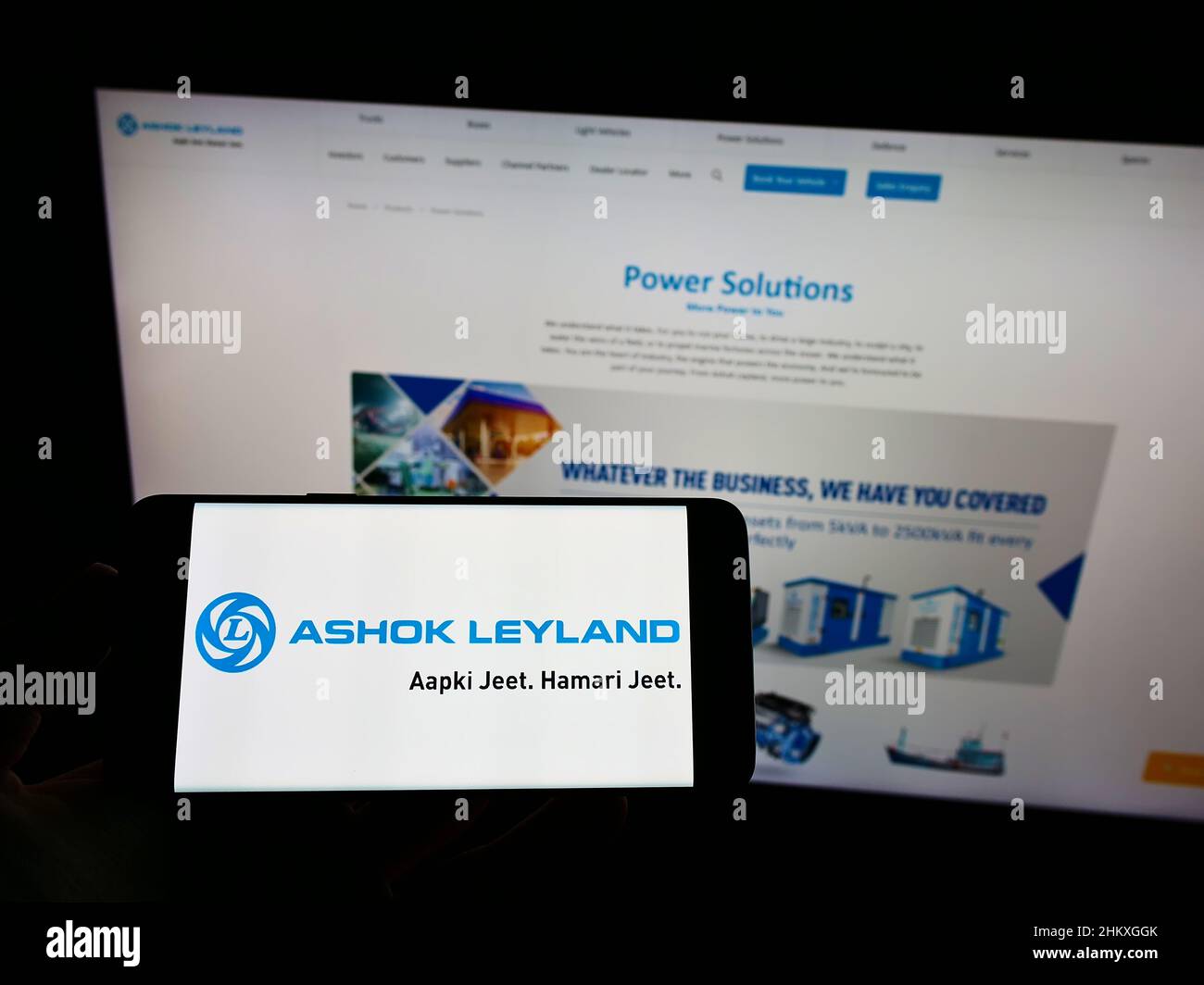 Person holding mobile phone with logo of Indian automotive company