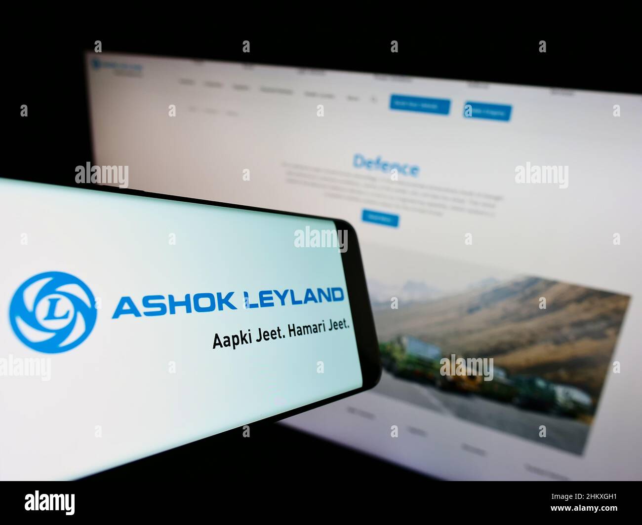 Mobile phone with logo of Indian automotive company Ashok Leyland Ltd. on screen in front of website. Focus on center-right of phone display. Stock Photo