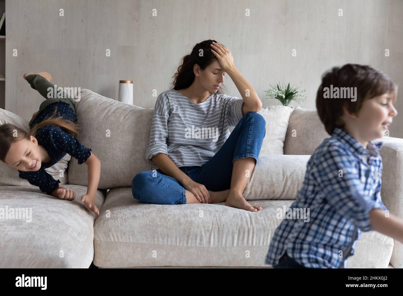 Tired young mother suffering from headache, exhausted by noisy kids Stock Photo