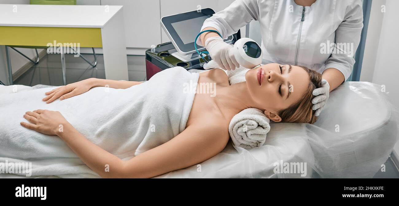 Removal of brown spots, freckles and rosacea on female face at cosmetology using machine with intense pulsed light IPL technology Stock Photo