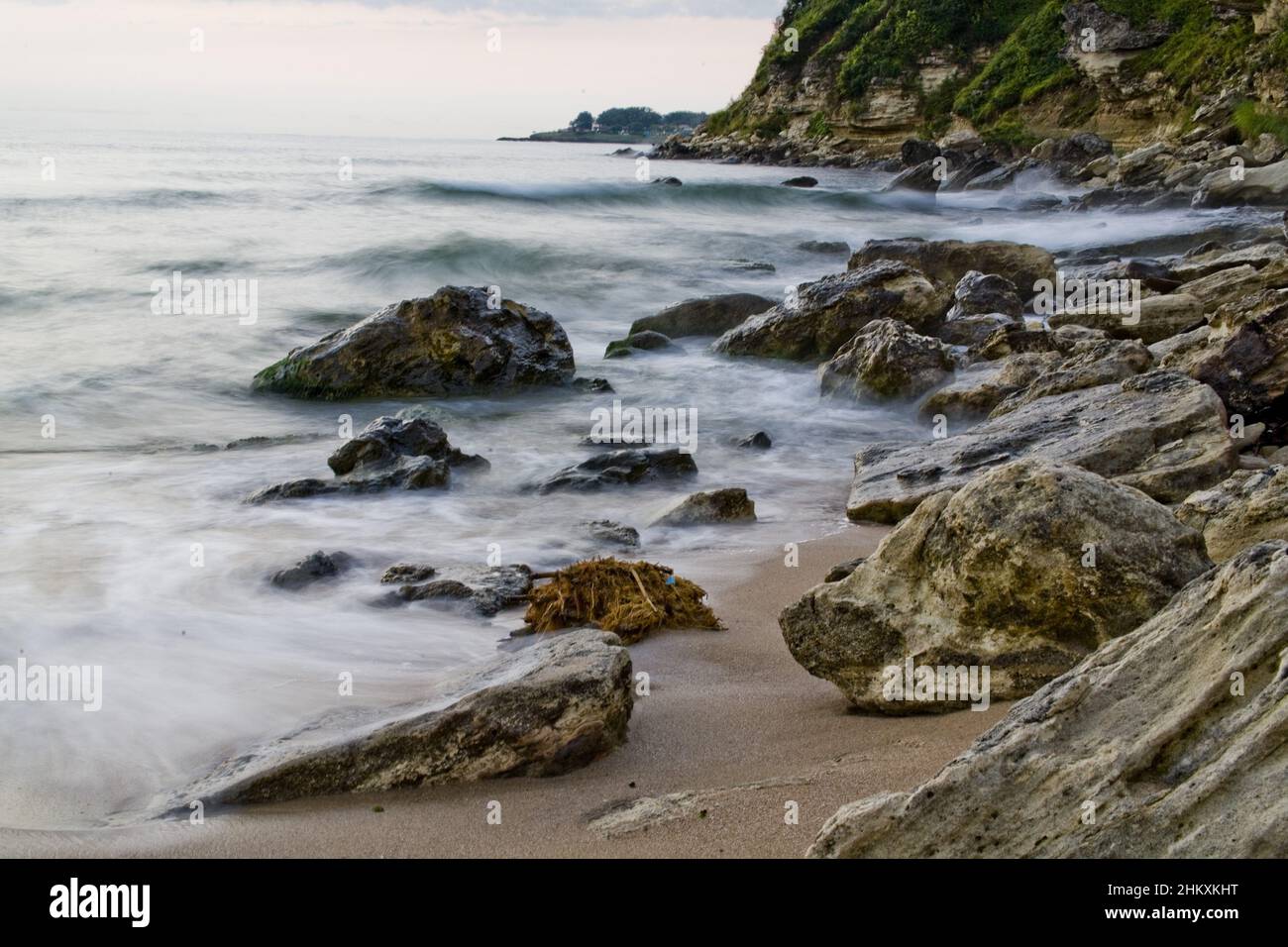 Rocky beach and calm water in long exposure Stock Photo - Alamy