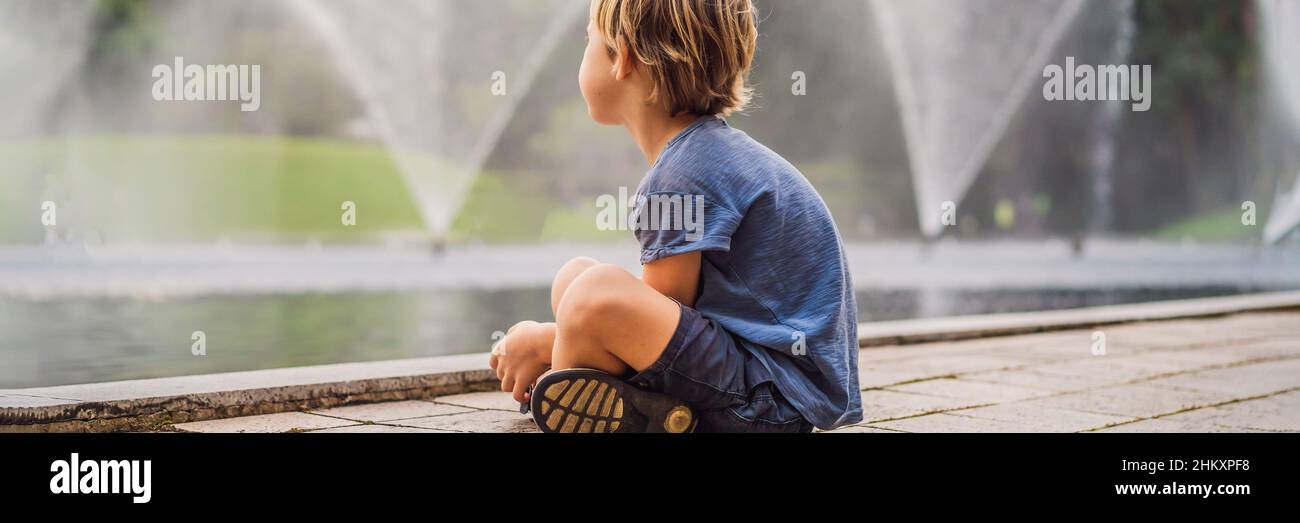 Boy on background of fountain on the lake in the evening near by twin