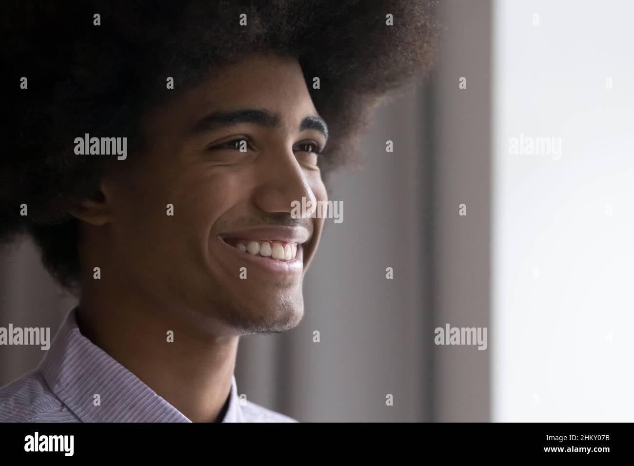 Happy African teenage guy with retro Afro hairstyle looking away Stock Photo