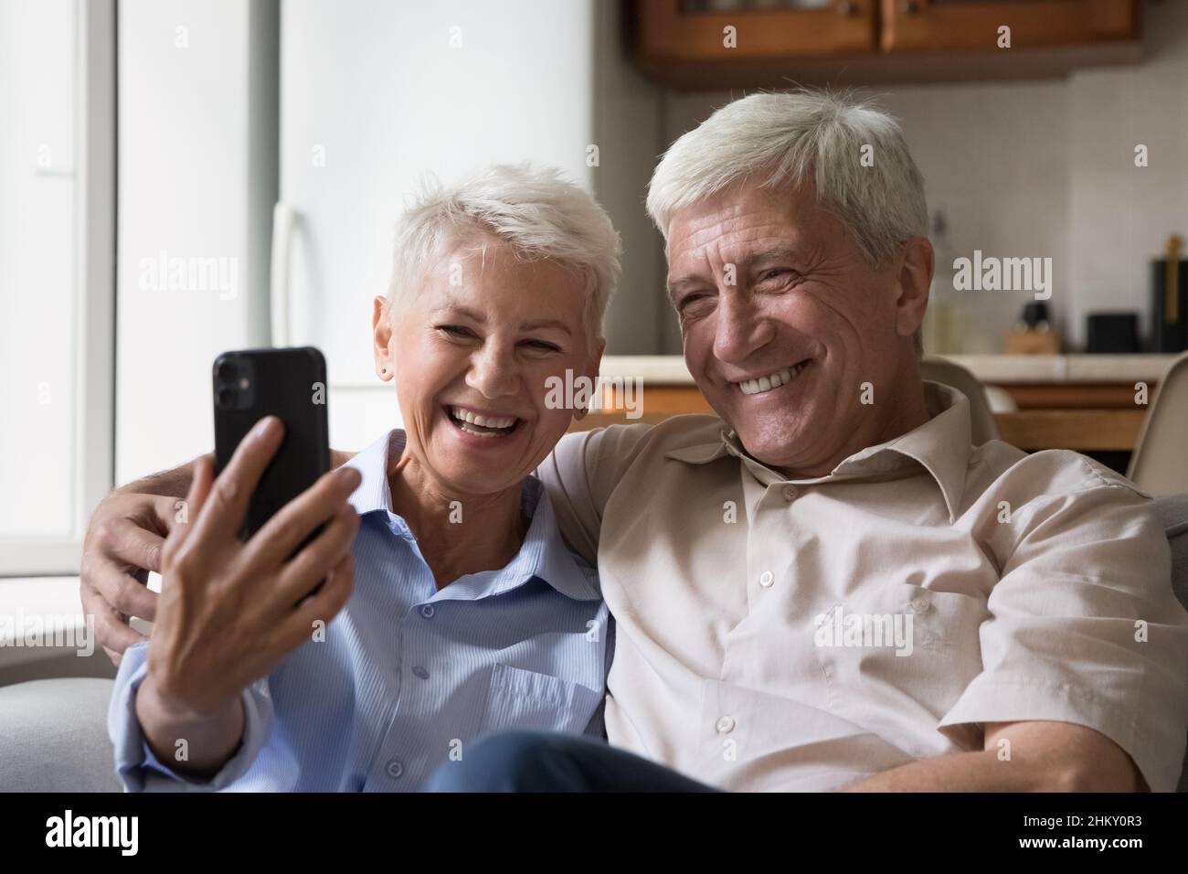 Happy joyful senior couple taking home selfie on mobile phone Stock Photo