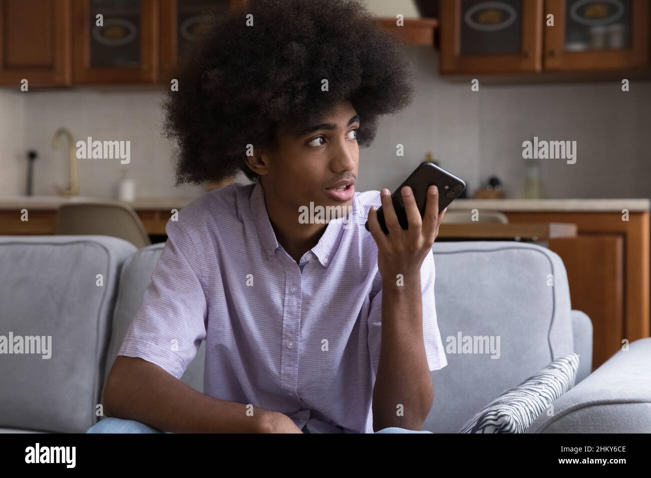 Serious teen African hipster guy recording audio message Stock Photo