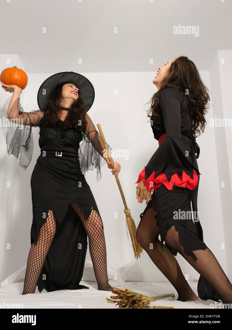 Two young latinas dressed as witches in halloween costumes having fun