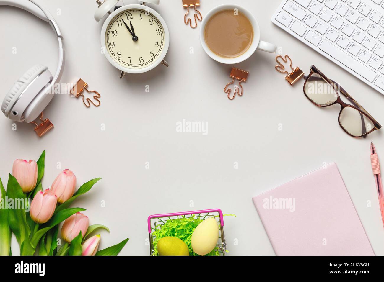Desktop. Notepad keyboard coffee cup alarm clock on the table with easter decorations. Frame border flat lay copy space top view Stock Photo