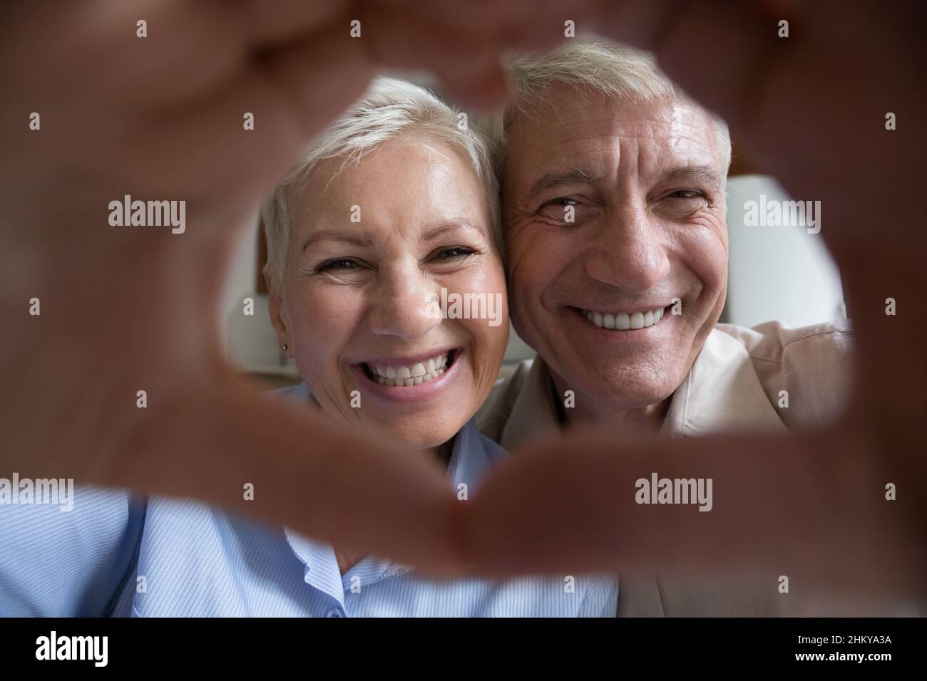 Happy mature elder couple portrait with hand heart shaped frame Stock Photo