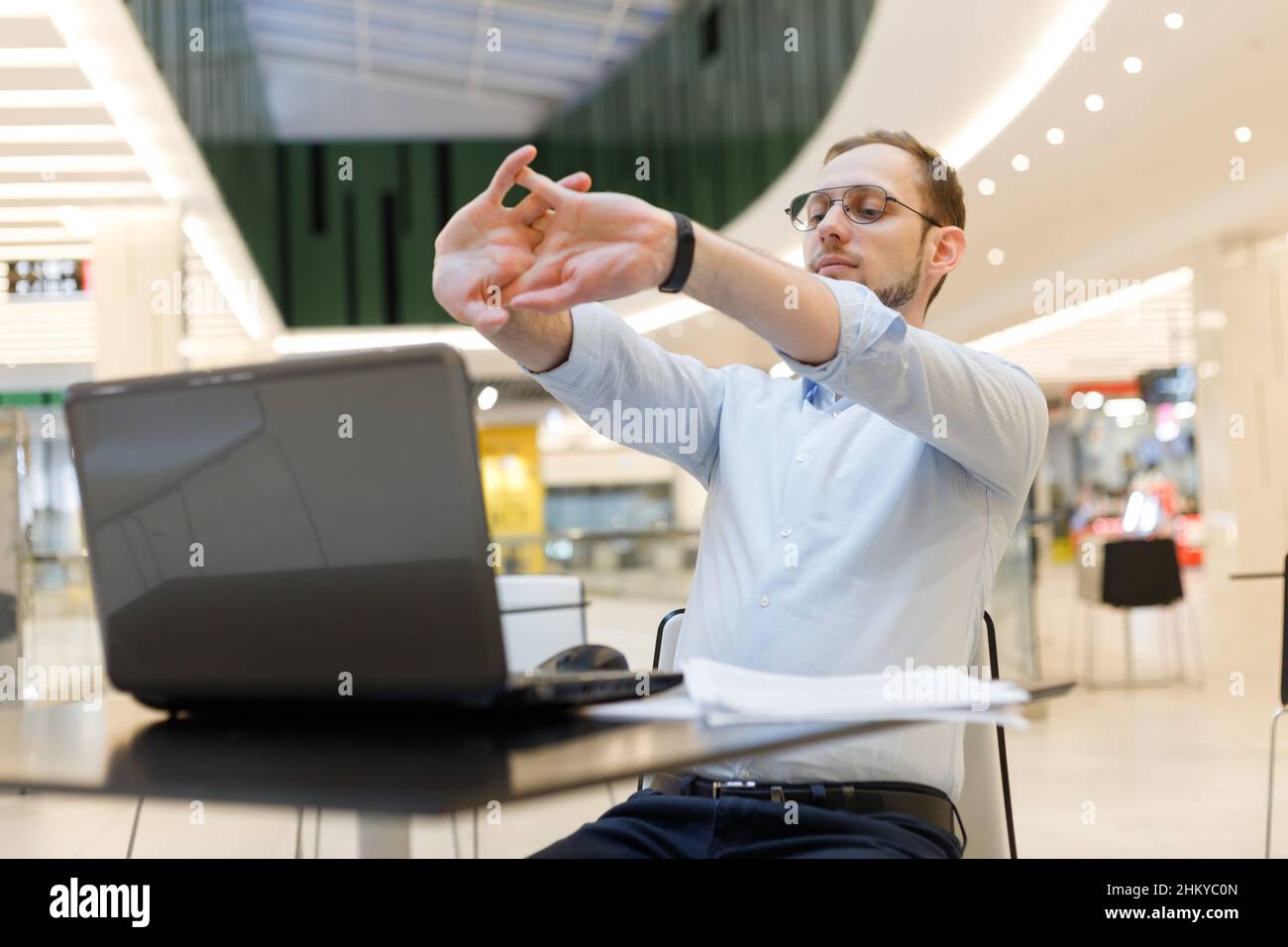 Freelancer man stretching arms while working at laptop. Prevention of
