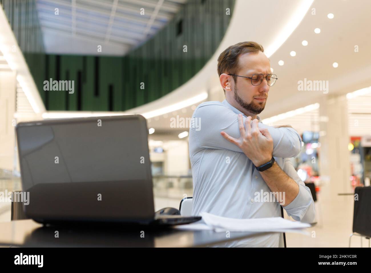 Freelancer man stretching arms while working at laptop. Prevention of