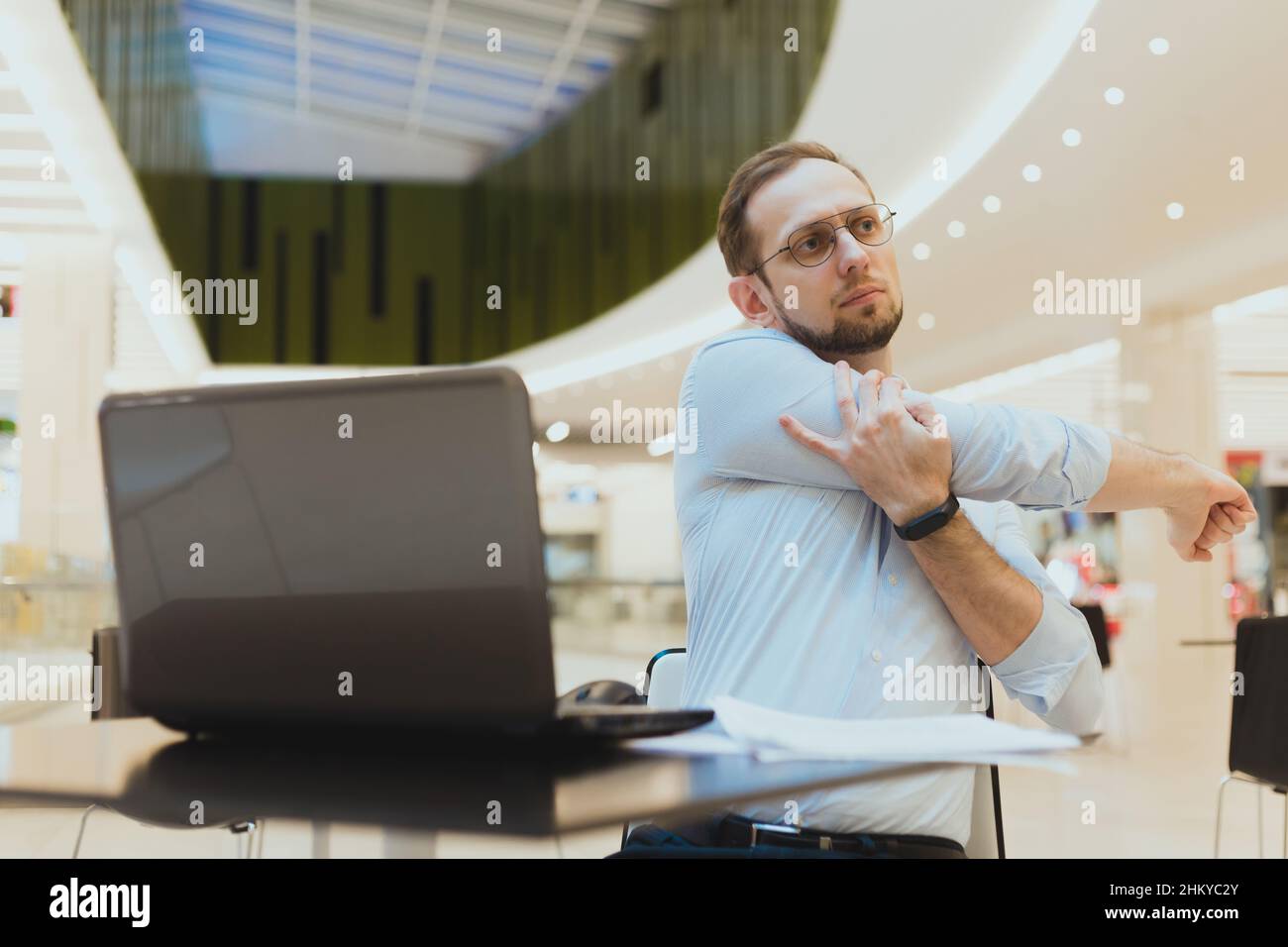 Freelancer man stretching arms while working at laptop. Prevention of