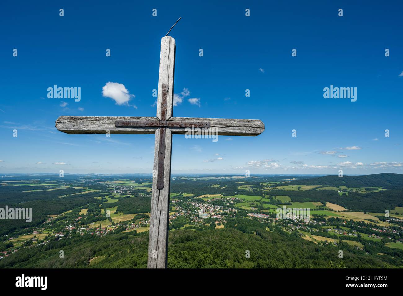 A cross on the top of the Oresnik rock lookout in the Jizera Mountains. In the background the village of Hejnice and the Frydlant region. Stock Photo