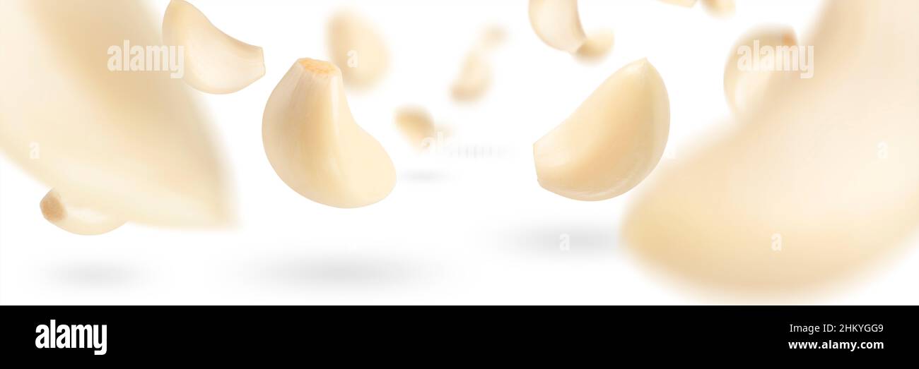 Set of peeled garlic cloves falling on a white background with ...