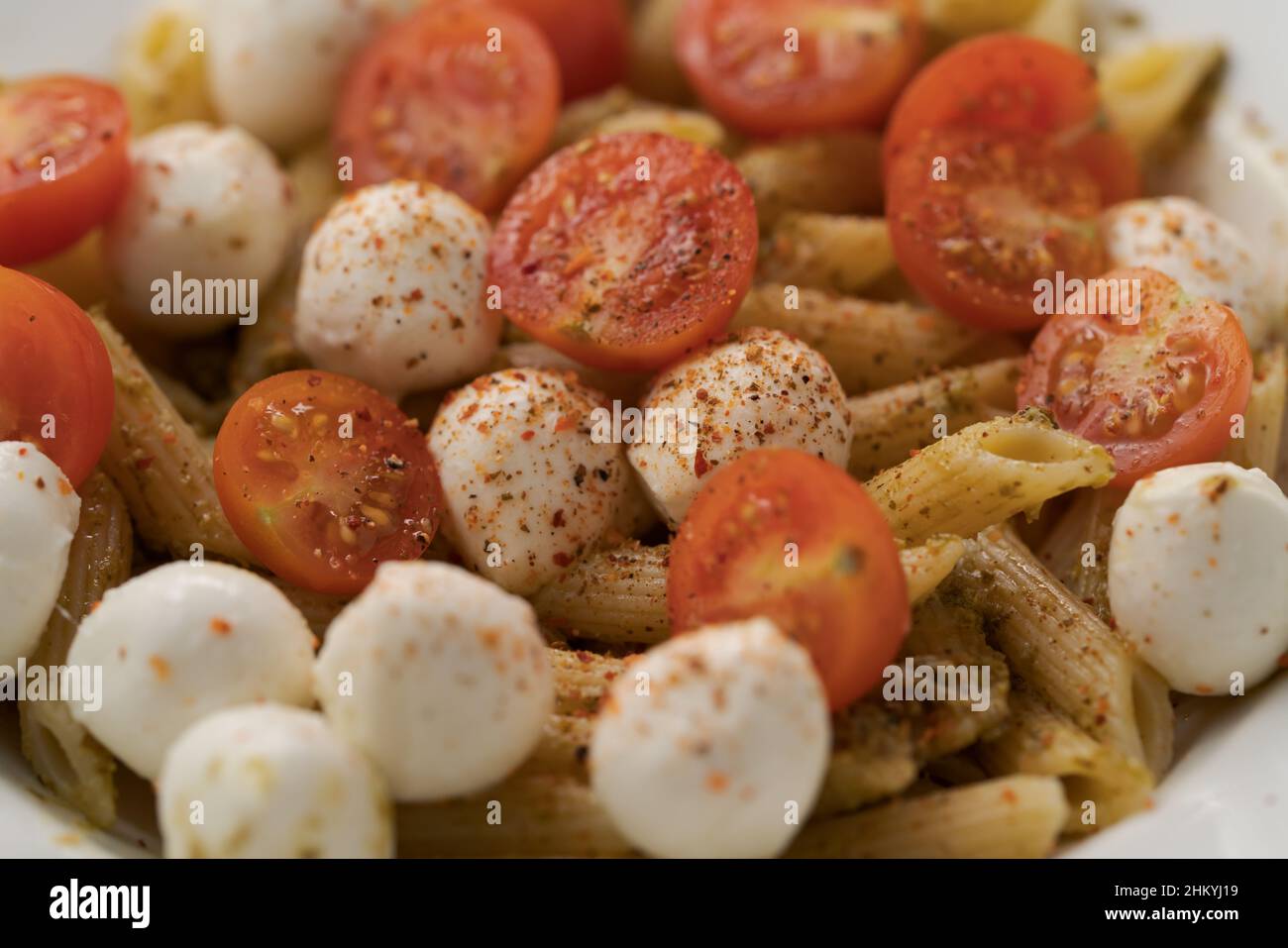 Penne pasta with mozzarella balls and cherry tomatoes, closeup Stock Photo