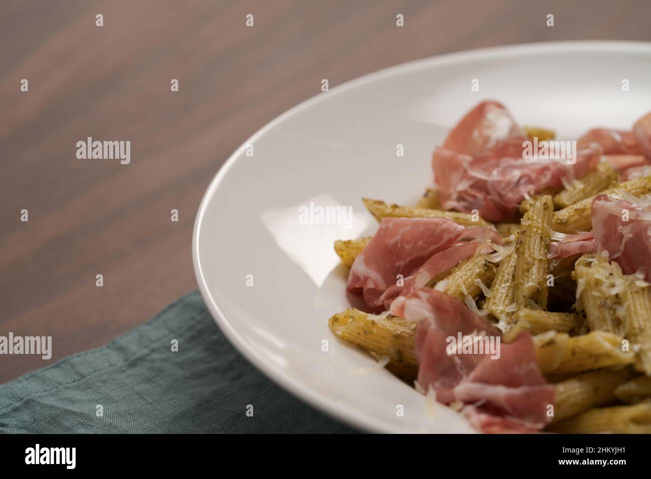 Penne pasta with capocollo, pesto and parmesan cheese, shallow focus