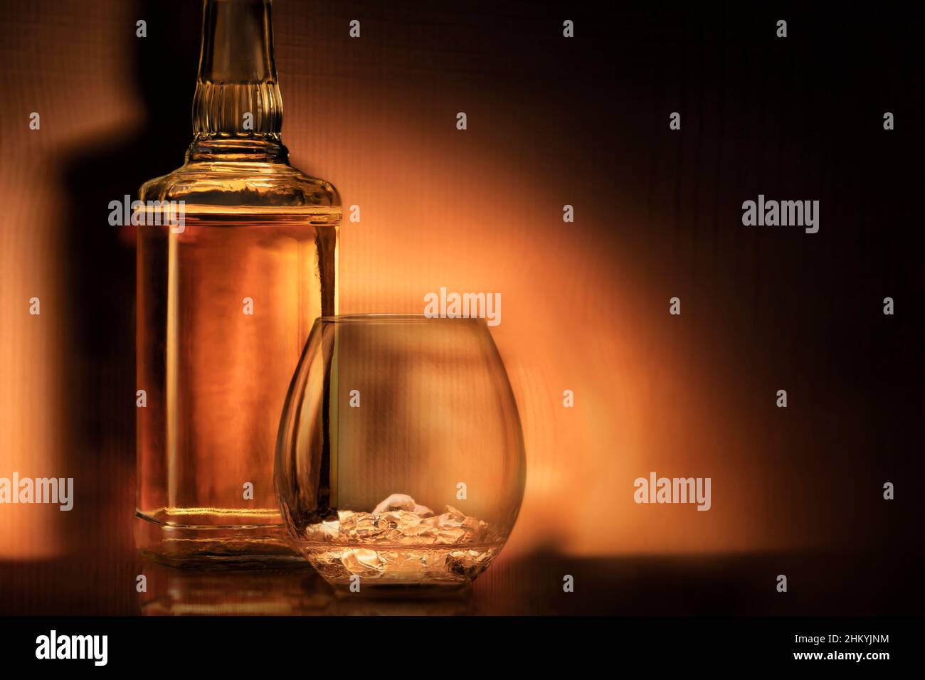 a bottle of rum , golden whiskey or liqueur . a glass of bourbon has a beautiful dark background