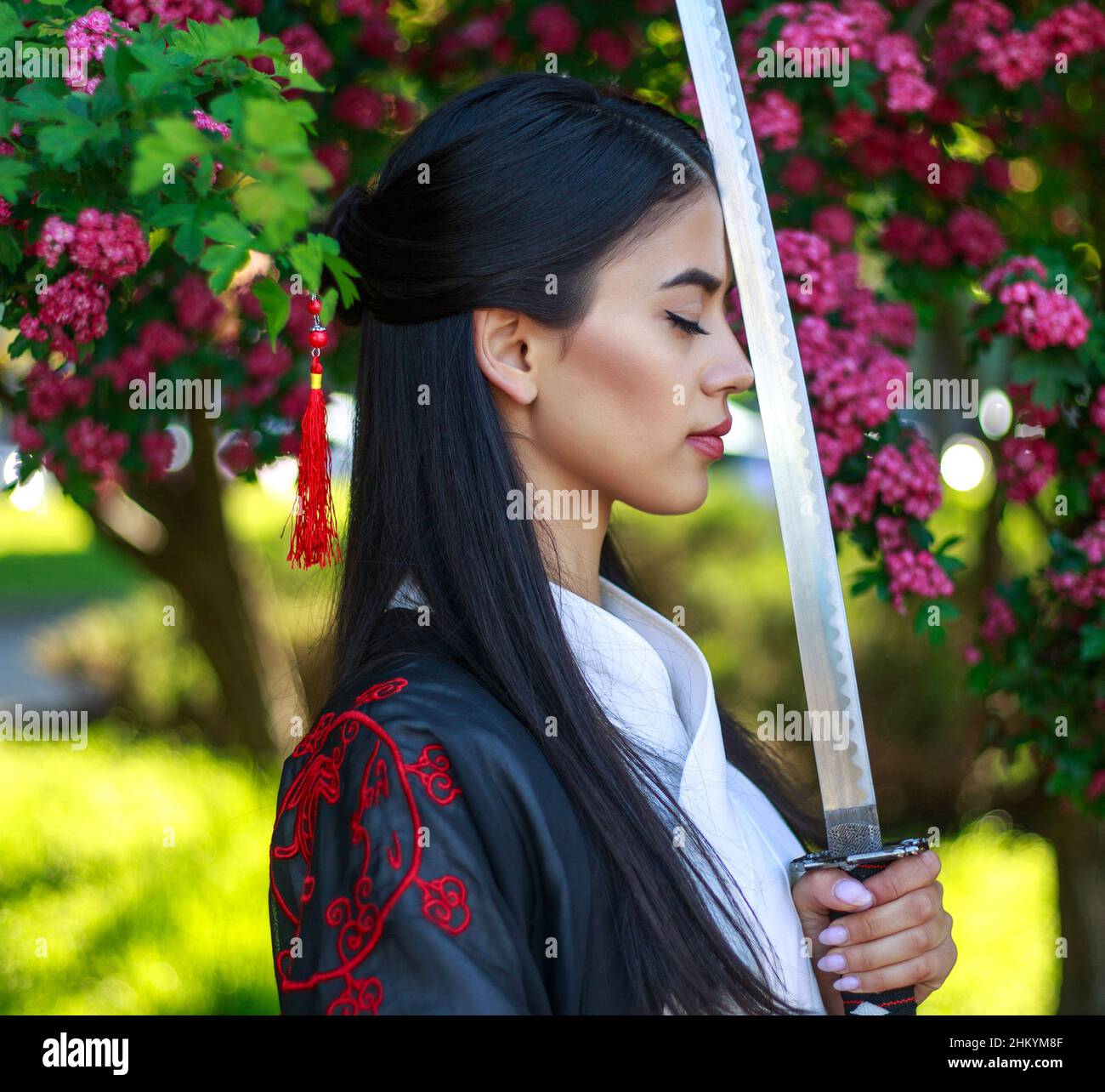 Young asian girl in a traditional kimano in a blooming garden with a samurai  japanese sword katana in the image of a warrior woman Stock Photo - Alamy