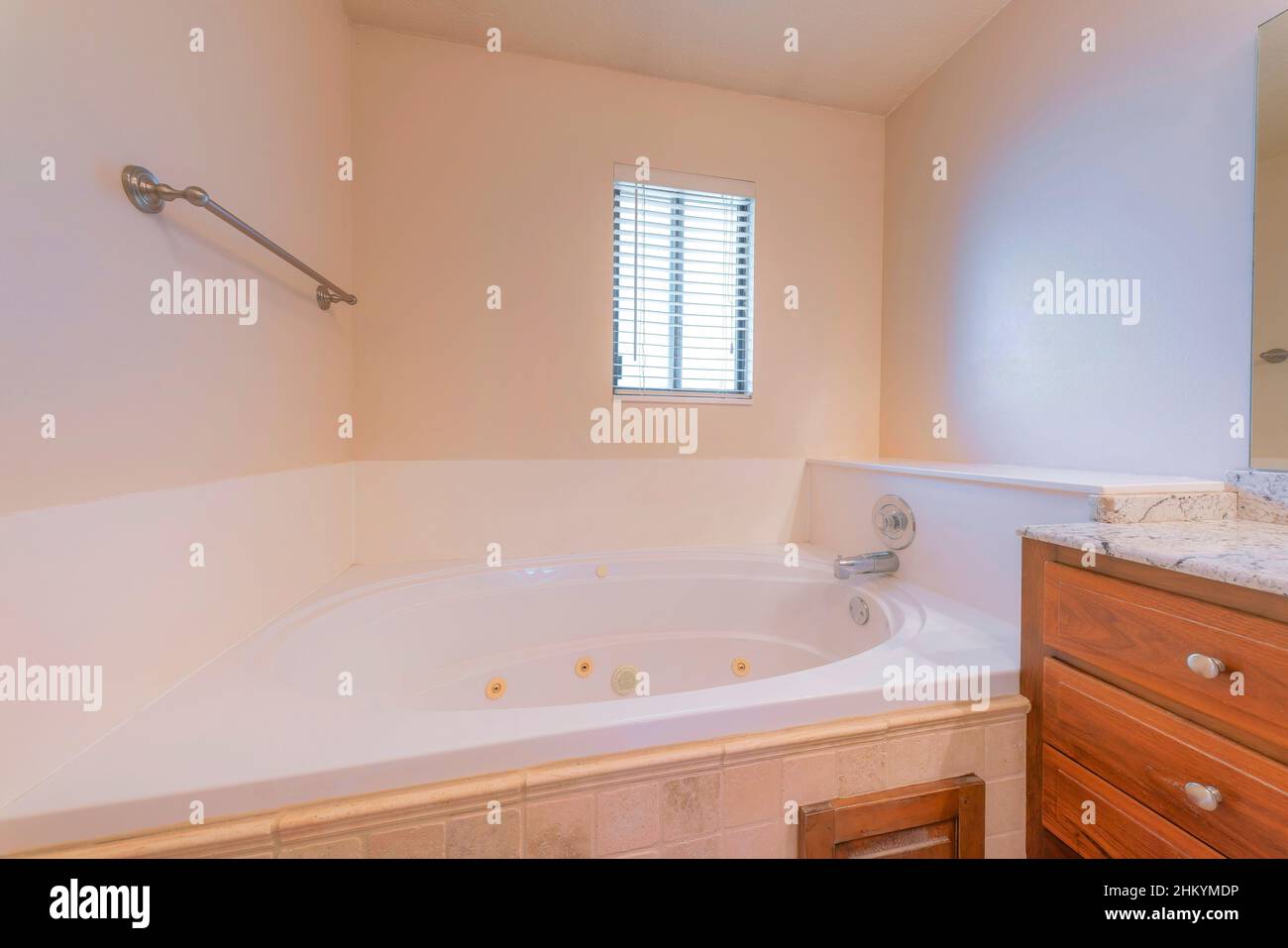 Alcove jacuzzi tub near the vanity with wood drawers Stock Photo Alamy