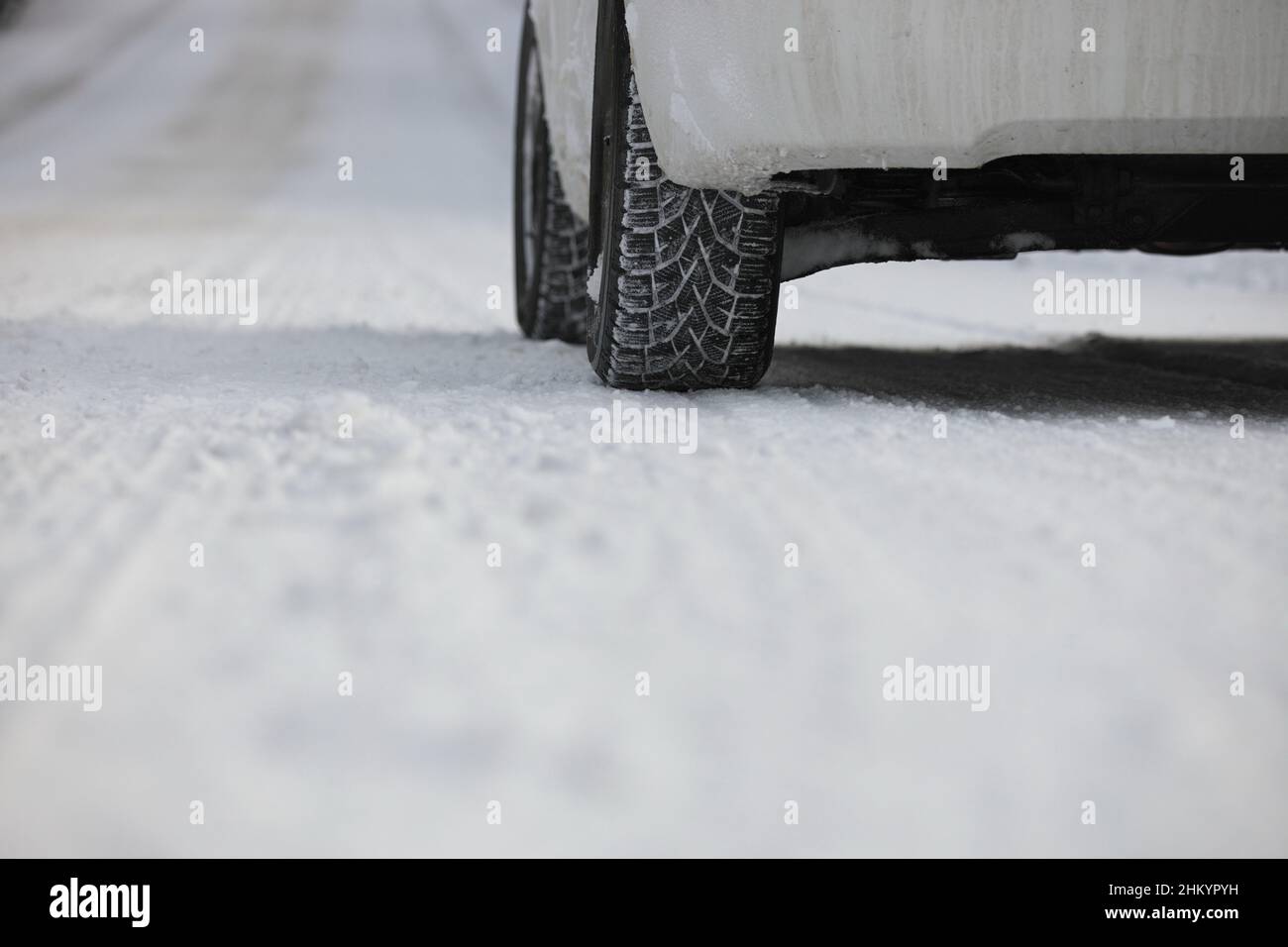 Close up of Winter Tire on Snow and Ice Covered Road Stock Photo