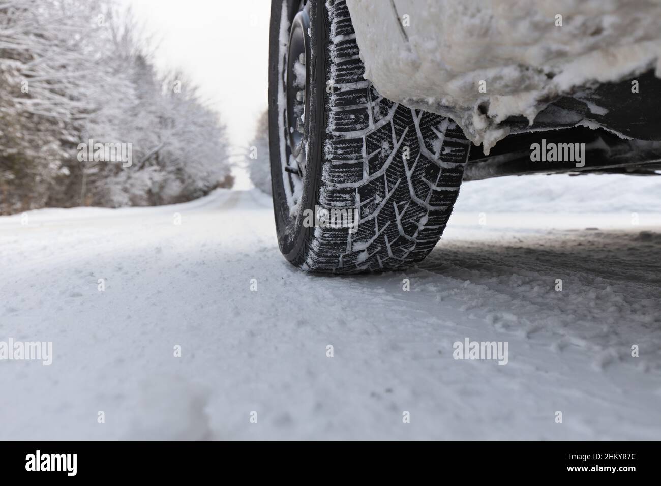 Close up of Winter Tire on Snow and Ice Covered Road Stock Photo