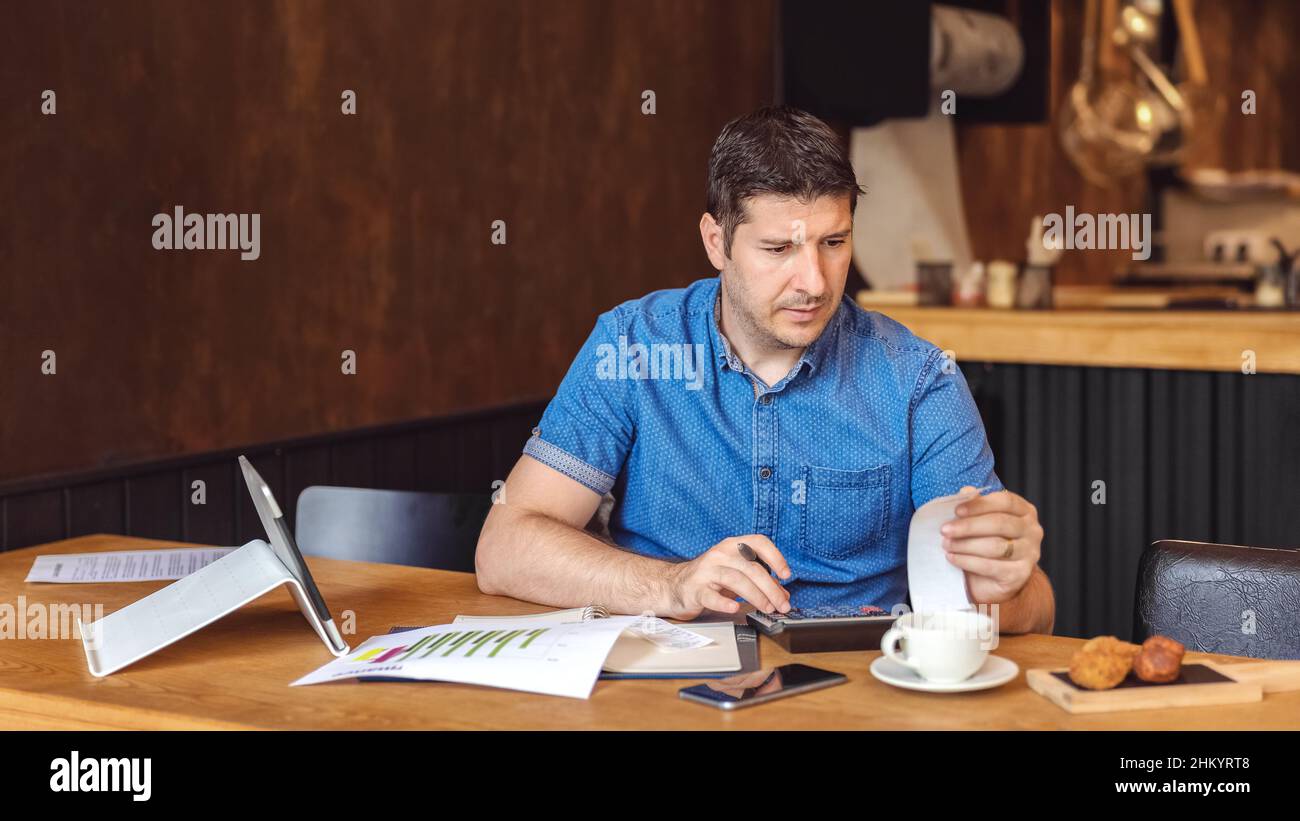 Mature new small business owner calculating online restaurant bill expenses and taxes Stock Photo