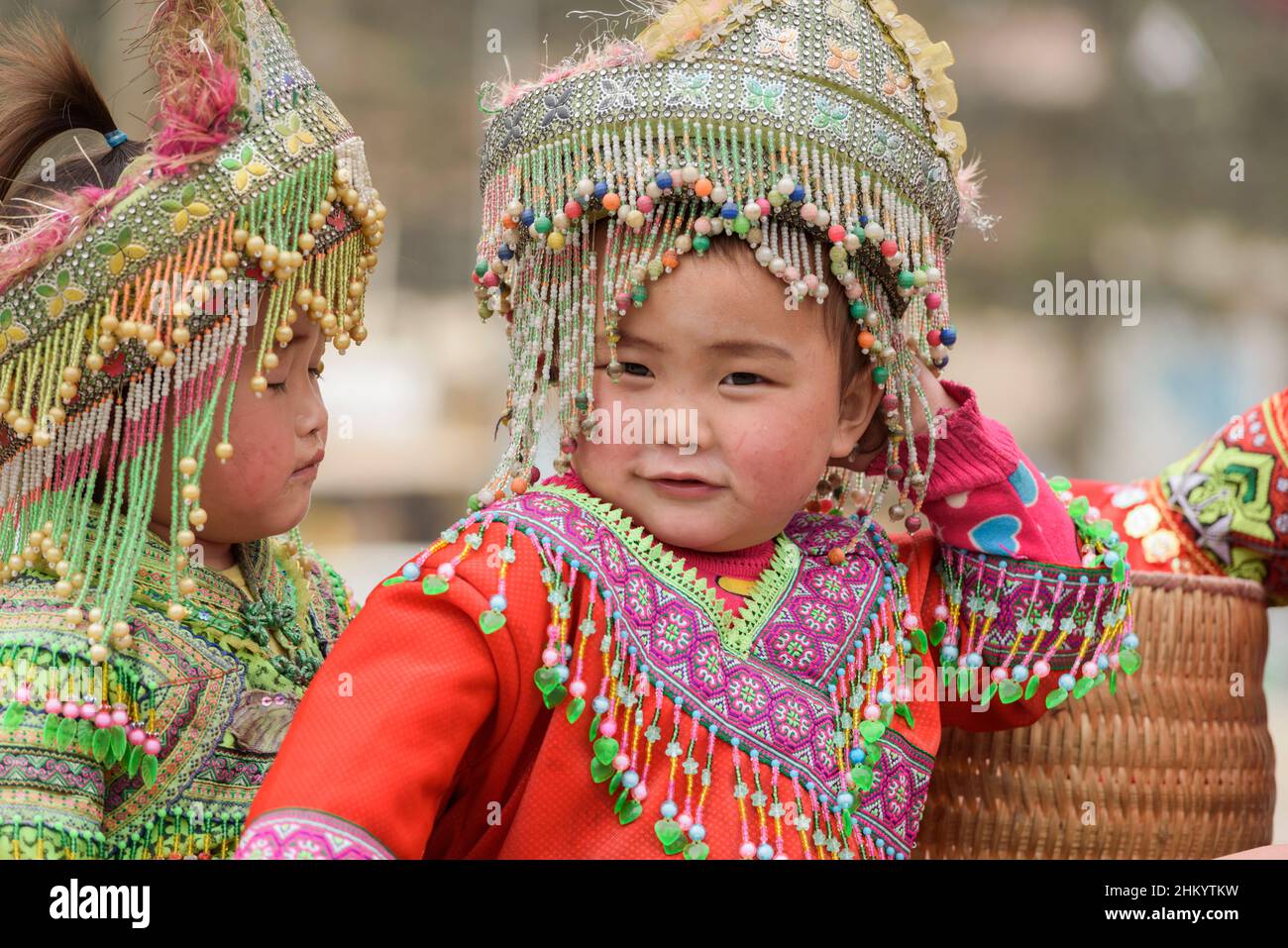 Young girls, wearing traditional Hmong tribe clothing, wait to pose for photographs by tourists in the town square, Sapa (Sa Pa), Lao Cai, Vietnam Stock Photo