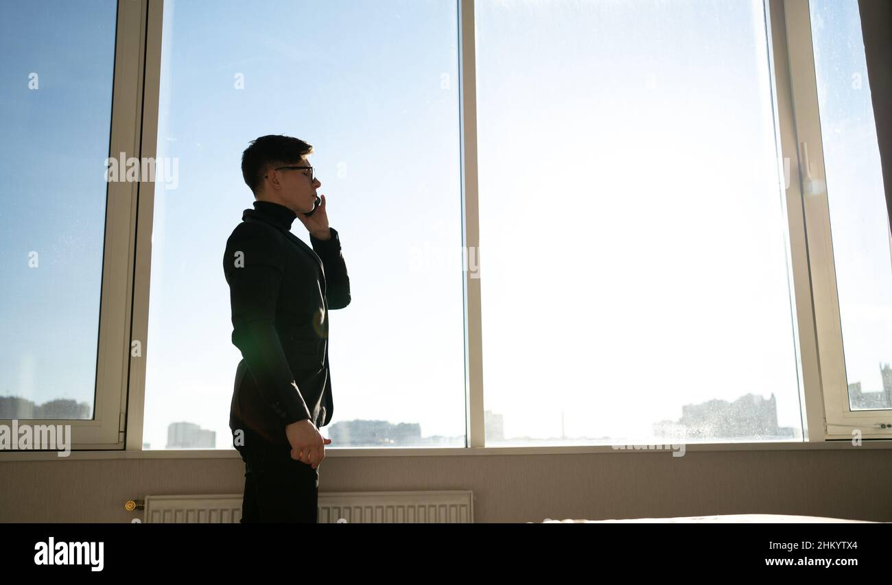 a male businessman stands in the office near the panoramic window ...