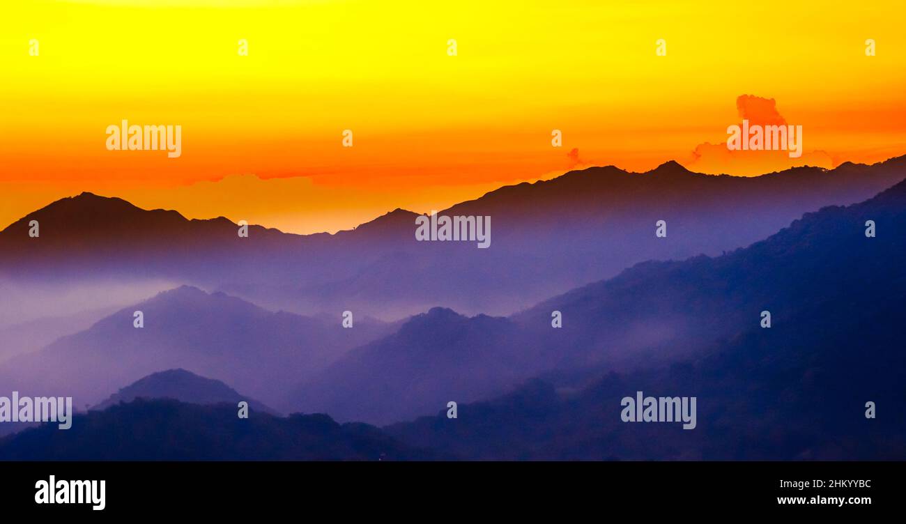 Purple Mountain Silhouette during sunset with fog in Minca, Colombia Stock Photo