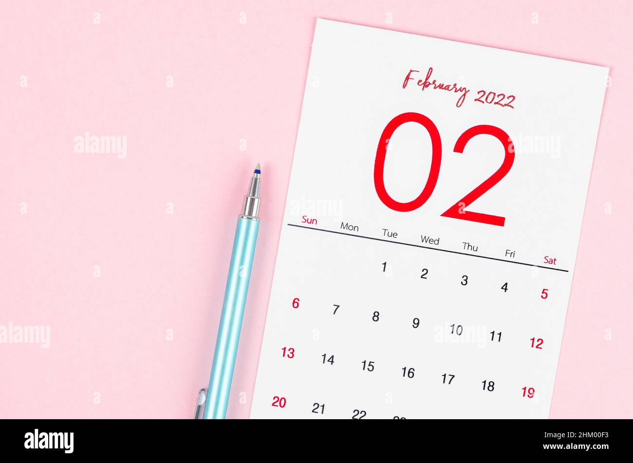 The February 2022 calendar with pen on pink background. Stock Photo