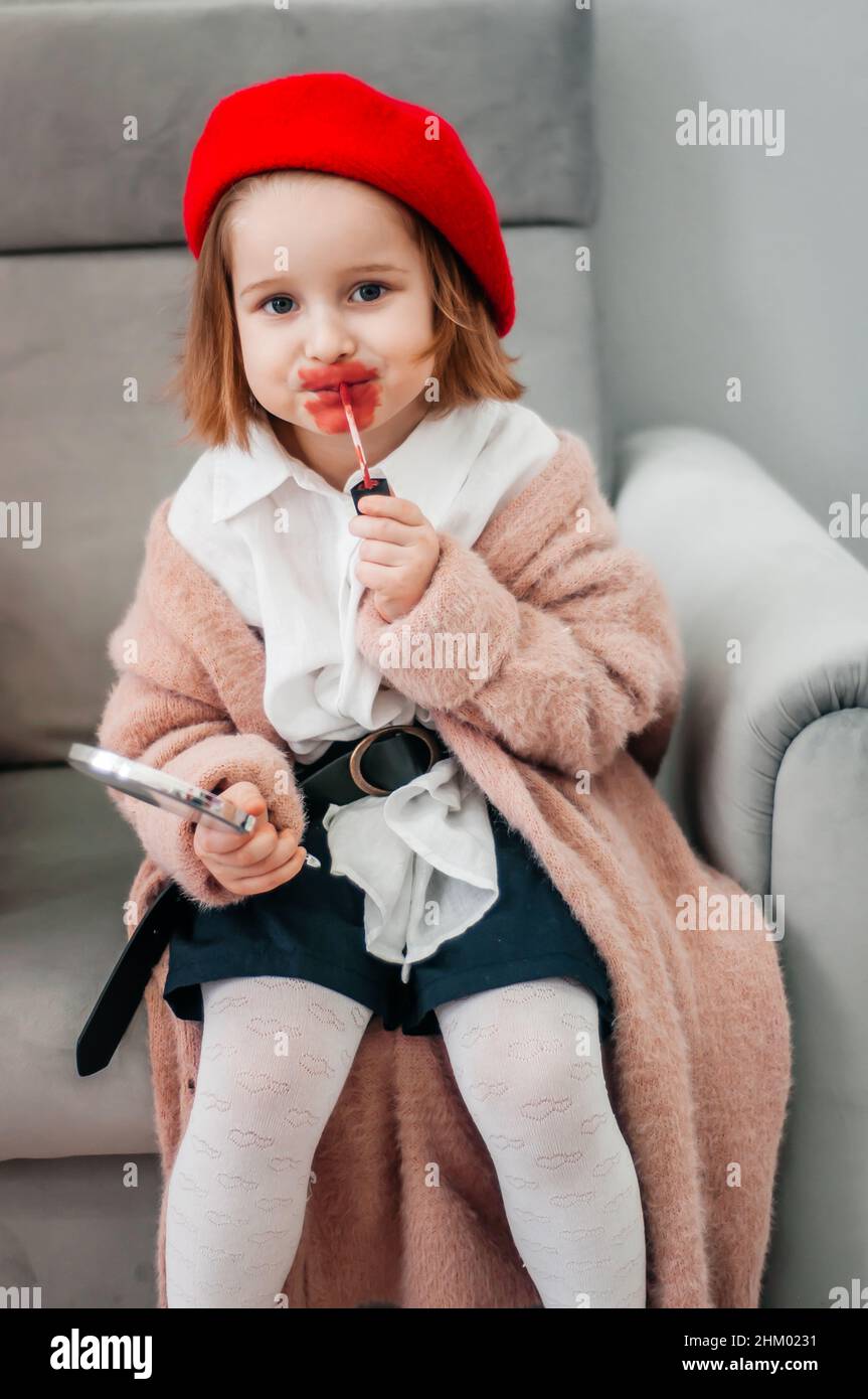 Red lipstick, bright baby lips. Fashionable child in a red beret and